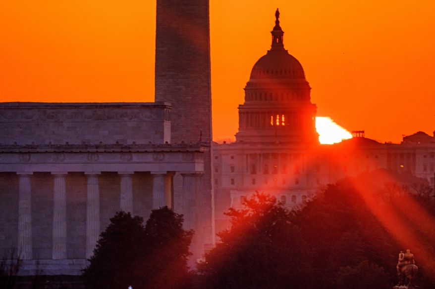 The sun flares through the camera lens as it rises behind the U.S. Capitol building, Washington Monument and the Lincoln Memorial, Monday, March 22, 2021, in Washington. Talk-radio host Michael Savage warns that the push during former President Barack Obama’s era for “hope and change” has intensified. (AP Photo/J. David Ake)