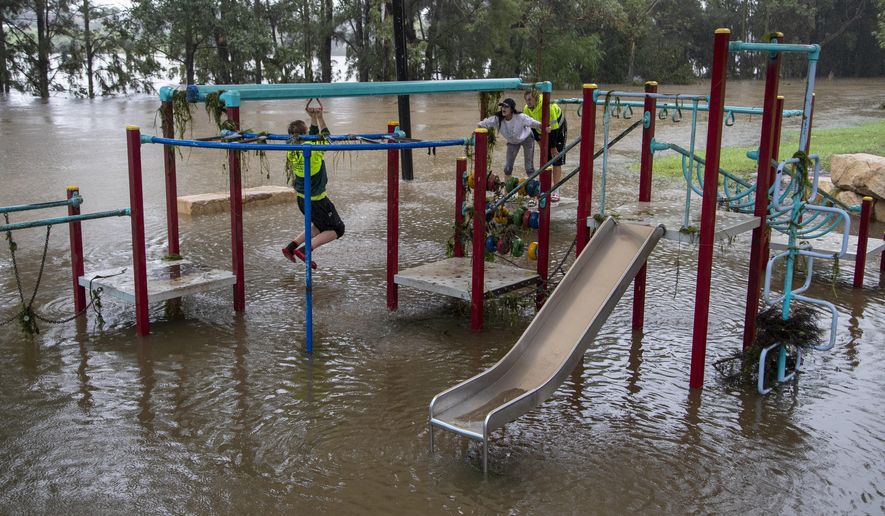 People play on equipment at a playground on the banks of the Nepean River at Jamisontown on the western outskirts of Sydney Monday, March 22, 2021. Australia&#39;s most populous state of New South Wales has issued more evacuation orders following the worst flooding in decades. (AP Photo/Mark Baker)