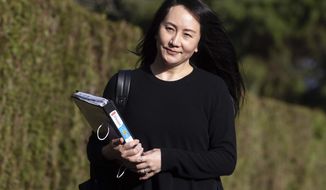 Meng Wanzhou, chief financial officer of Huawei, carries a binder of documents as she leaves her home to attend a hearing at British Columbia Supreme Court, in Vancouver, on Monday, March 22, 2021. (Darryl Dyck/The Canadian Press via AP)