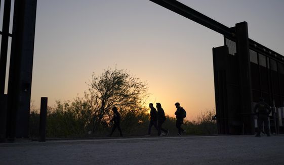 Migrants walk near a gate on the U.S.-Mexico border wall after they were spotted by a U.S. Customs and Border Protection agent and taken into custody while trying to cross, Sunday, March 21, 2021, in Abram-Perezville, Texas. The fate of thousands of migrant families who have recently arrived at the Mexico border is being decided by a mysterious new system under President Joe Biden. U.S. authorities are releasing migrants with “acute vulnerabilities” and allowing them to pursue asylum. But it’s not clear why some are considered vulnerable and not others. (AP Photo/Julio Cortez) **FILE**