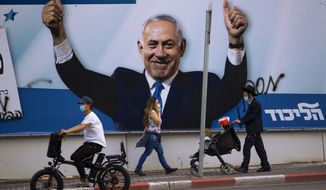 People pass an election campaign billboard for the Likud party that shows a portrait of its leader Prime Minister Benjamin Netanyahu, in Ramat Gan, Israel, Sunday, March 21, 2021. Israelis head to the polls on Tuesday for what will be the fourth parliamentary election in just two years. Once again, the race boils down to a referendum on Prime Minister Benjamin Netanyahu. (AP Photo/Oded Balilty)