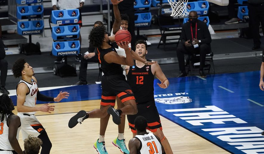 Oregon State guard Ethan Thompson (5) drives on Oklahoma State forward Matthew-Alexander Moncrieffe (12) during the second half of a men&#39;s college basketball game in the second round of the NCAA tournament at Hinkle Fieldhouse in Indianapolis, Sunday, March 21, 2021. (AP Photo/Paul Sancya)