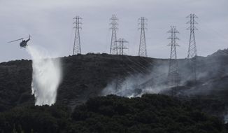 FILE - In this Oct. 10, 2019, file photo, a helicopter drops water near power lines and electrical towers while working at a fire on San Bruno Mountain near Brisbane, Calif. A federal judge overseeing Pacific Gas &amp;amp; Electric&#39;s criminal probation is considering requiring the utility to be more aggressive about turning off its electricity lines. The plan outlined Tuesday, March 23, 2021, would add more power shut-offs near tall trees and would at least double the number of power outages in six Northern California counties. (AP Photo/Jeff Chiu, File)