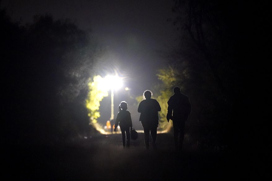 A 7-year-old migrant girl from Honduras, left, walks with Fernanda Solis, 25, center, also of Honduras, and an unidentified man as they approach a U.S. Customs and Border Protection processing center to turn themselves in while seeking asylum moments after crossing the U.S.-Mexico border, Sunday, March 21, 2021, in Mission, Texas. The girl's journey illustrates the extraordinary risks taken by parents to get their children across the border, even if it means abandoning them for the most perilous part of the trip. She is one of thousands of kids arriving alone in the U.S. in a surge that is straining the federal government’s system for managing refugees. (AP Photo/Julio Cortez)