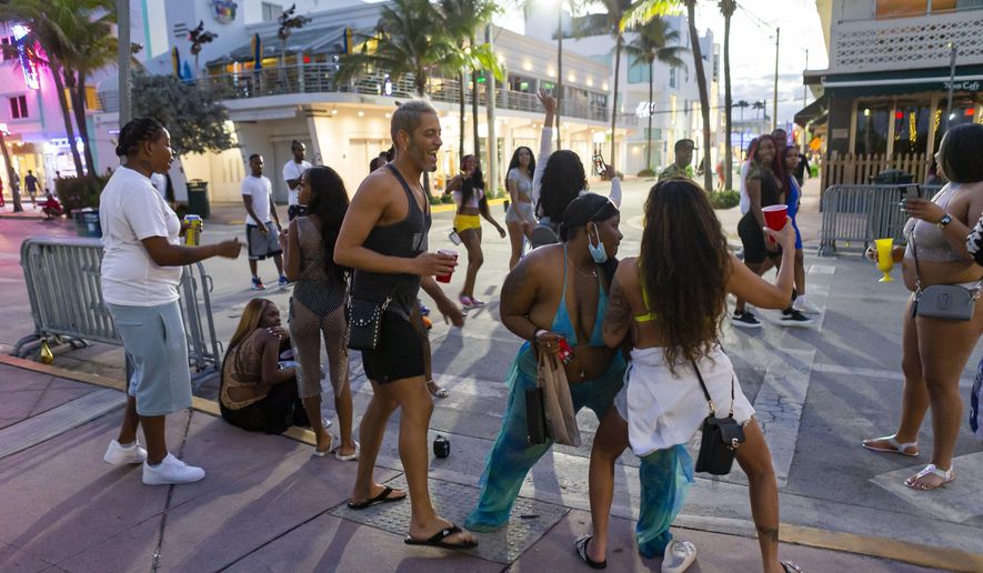 A group of tourists dance on Ocean Drive during Spring Break in Miami Beach, Fla., Monday, March 22, 2021. A party-ending curfew is in effect in Miami Beach, imposed after fights, gunfire, property destruction and dangerous stampedes broke out among huge crowds of people. The curfew could extend through the end of spring break.(Matias J. Ocner/Miami Herald via AP)