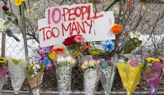 A sign stands above floral bouquets lined along the temporary fence around a King Soopers grocery store, which is where 10 victims died on Monday in a mass shooting, Wednesday, March 24, 2021, in Boulder, Colo. (AP Photo/David Zalubowski)