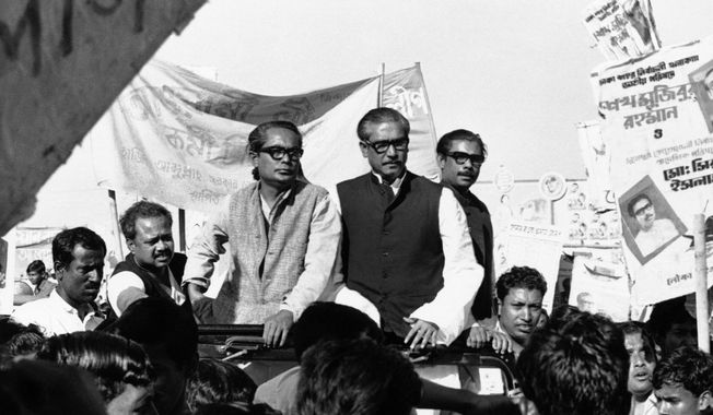 FILE- In this Dec. 7, 1970, file photo, Sheikh Mujibur Rahman, center on Rostrum, leader of East Pakistan&#x27;s powerful Awami League, addresses an election rally in Dacca, East Pakistan. A watershed moment occurred in 1970 amid strikes and rising hostilities, when East Pakistan’s Awami League, led by Bengali politician Sheikh Mujibur Rahman, swept the polls in a national election. The government rejected the results, spawning a civil disobedience movement. On March 26, 1971, Bangladesh declared independence, sparking the nine-month war. Pakistan launched a military operation to stop the move to independence, while India joined on the side of what is now Bangladesh. Pakistani forces surrendered on Dec. 16, 1971. (AP Photo/Dennis Lee Royle, File)