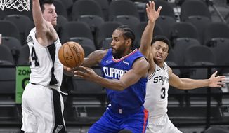 Los Angeles Clippers&#39; Kawhi Leonard, center, passes the ball as he is defended by San Antonio Spurs&#39; Drew Eubanks, left, and Keldon Johnson during the first half of an NBA basketball game on Wednesday, March 24, 2021, in San Antonio. (AP Photo/Darren Abate)