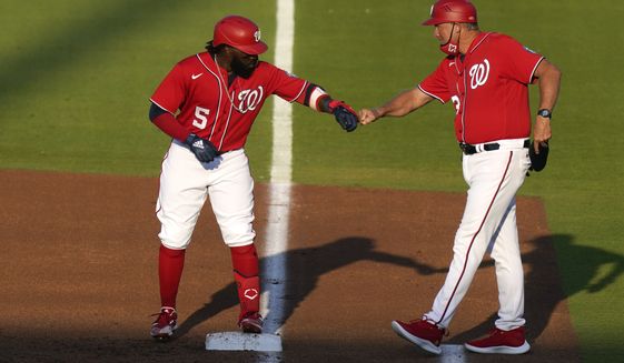 Washington Nationals&#x27; Josh Harrison (5) bumps fists with first base coach Randy Knorr after hitting a single during the first inning of a spring training baseball game against the Houston Astros, Wednesday, March 24, 2021, in West Palm Beach, Fla. (AP Photo/Lynne Sladky)