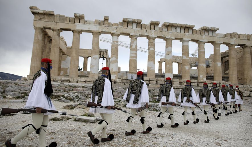 Members of the Presidential Guard walk in front of the Parthenon temple atop of Acropolis Hill before the Greek flag raising ceremony in Athens, Thursday, March 25, 2021. Greece celebrates the bicentenary of the start of the country&#39;s war of independence against the Ottoman Empire. (AP Photo/Petros Giannakouris, Pool)