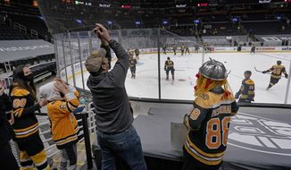 A Boston Bruins fan catches a puck tossed by a player during pre-game warm-ups in TD Garden before an NHL hockey game between the Bruins and the New York Islanders, Thursday, March 25, 2021, in Boston. This is the first game of the 2021 season allowing limited fan attendance in the arena. (AP Photo/Elise Amendola)