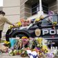 In this March 23, 2021, photo, a man leaves a bouquet on a police cruiser parked outside the Boulder Police Department after an officer was one of the victims of a mass shooting at a King Soopers grocery store in Boulder, Colo. The suspects in the most recent shooting sprees found it relatively easy to get their guns. The suspect in the shooting at a Boulder supermarket was convicted of assaulting a high school classmate but still got a gun.(AP Photo/David Zalubowski)