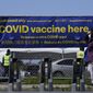 A pedestrian wears a face mask while walking past a sign at a vaccination center at City College of San Francisco during the coronavirus pandemic in San Francisco, Thursday, March 25, 2021. (AP Photo/Jeff Chiu) ** FILE **