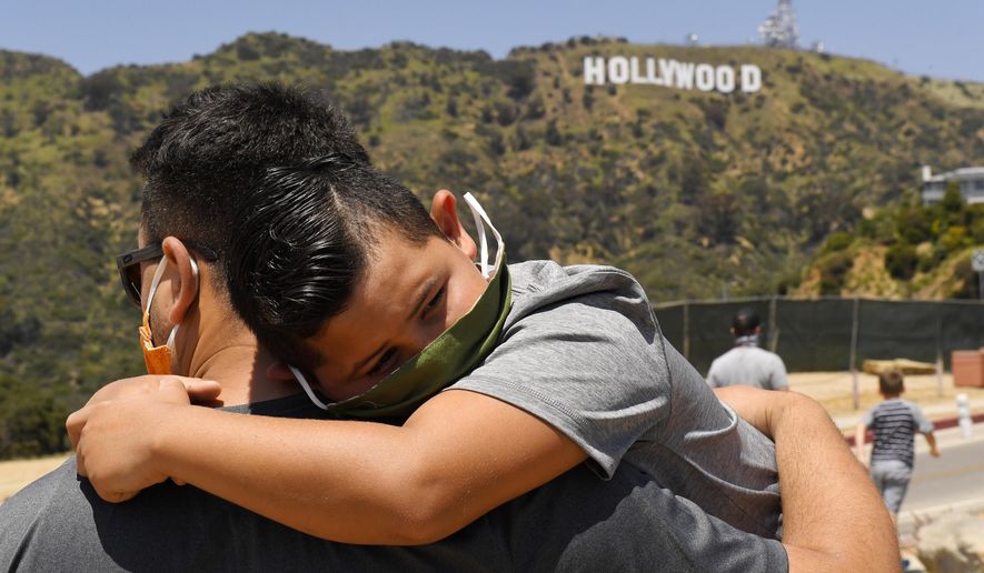 FILE - In this May 15, 2020, file photo, a father holds his son near the famed Hollywood sign during the coronavirus outbreak in Los Angeles. (AP Photo/Mark J. Terrill, File)
