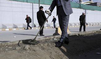 An Afghan security official looks for mines or improvised explosive device with metal detector on a roadside during a trip organized by the police for The Associated Press, in Kabul, Afghanistan, March 17, 2021. Sticky bombs slapped onto cars trapped in Kabul’s chaotic traffic are the newest weapons terrorizing Afghans in the increasingly lawless nation. The surge of bombings comes as Washington searches for a responsible exit from decades of war. (AP Photo/Rahmat Gul)