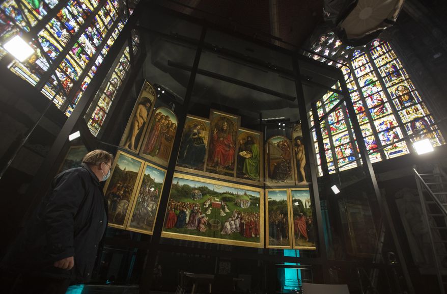 A man views the panels of the Ghent Altarpiece, by Flemish painter Jan Van Eyck, at Saint Bavo Cathedral in Ghent, Belgium on Monday, March 22, 2021. The Saint Bavo Cathedral will open a new visitors center where the restored Ghent Altarpiece will be the focal point. The 1934 theft of one of the panels, the Just Judges, and the restoration of the work, are testament to perhaps one of the greatest unsolved art crimes of all time. (AP Photo/Virginia Mayo)