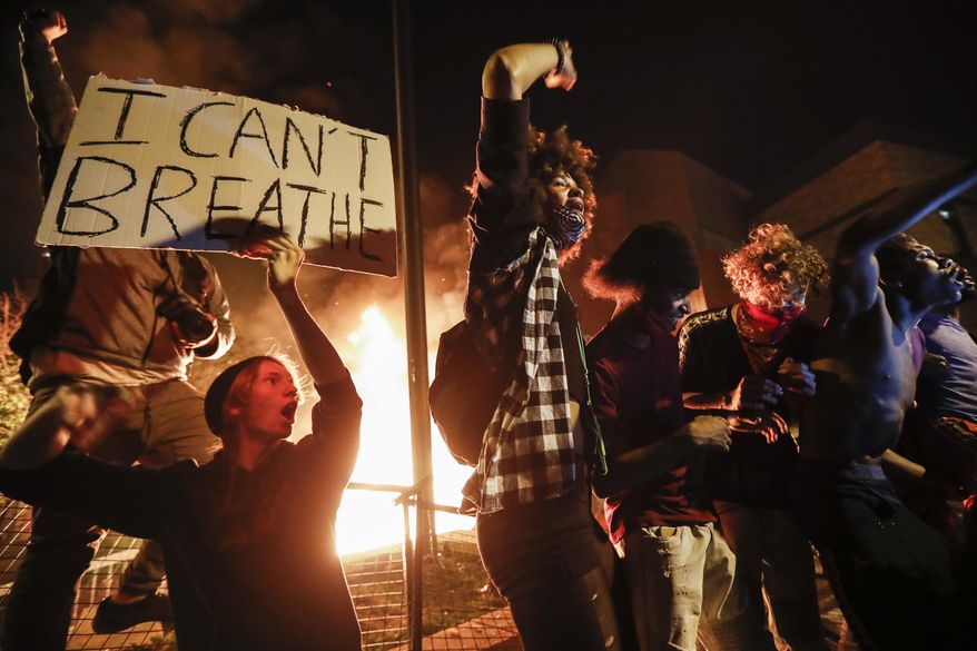 In this May 28, 2020, protesters demonstrate outside of a burning Minneapolis 3rd Police Precinct in Minneapolis. (AP Photo/John Minchillo, File) **FILE**