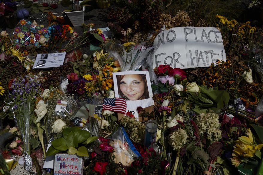 FILE - This photo from Wednesday Aug. 16, 201, shows a photo of Heather Heyer, who was killed during a white nationalist rally, surrounded with flowers at a memorial paying tribute to her life at the Paramount Theater, Charlottesville, Va. In a nation founded on whiteness, experts share perspective on whether it can be discussed. If white people want the future to be different, said Rev. Susan Chorley, a Boston area pastor, they have to be willing to look at the past and the present. "I think it's on us," she said. (AP Photo/Evan Vucci, File)