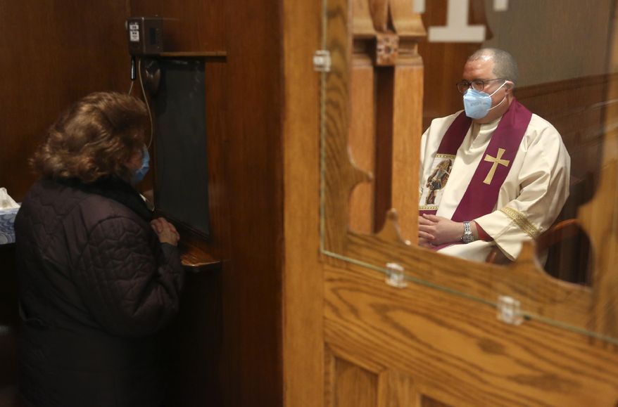 The Rev. Manuel Rodriguez listens to a parishioner&#39;s confession at Our Lady of Sorrows in the Queens borough of New York on Saturday, March 20, 2021. The Roman Catholic church reopened for in-person services in July 2020 and recently resumed in-person confessions. (AP Photo/Jessie Wardarski)