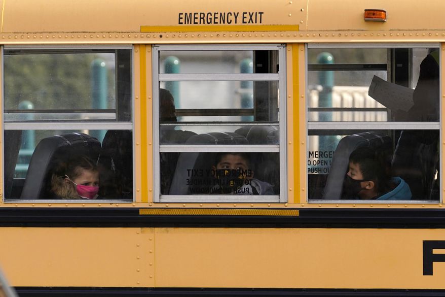Elementary school students sit on board a school bus after attending in-person classes at school in Wheeling, Illinois, Nov. 19, 2020. (AP Photo/Nam Y. Huh) ** FILE **