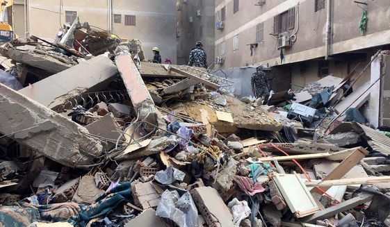 Emergency workers sift through the rubble of a collapsed apartment building in the el-Salam neighborhood, Saturday, March 27, 2021, in Cairo, Egypt. A nine-story apartment building collapsed in the Egyptian capital early Saturday, killing numerous people and injuring dozen more, said Khalid Abdel-Al, the administrative head of the Cairo government. (AP Photo/Mohamed Salah)