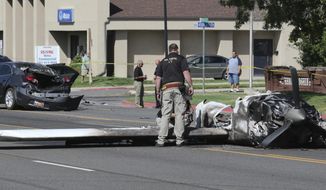 FILE - In this Sept. 12, 2017, file photo, an investigator looks at the wreckage of a small plane which struck a car, in the back ground, when it crashed into a neighborhood, in Roy, Utah. Utah has a new law requiring general aviation pilots with airplanes to carry at least $100,000 in liability insurance, inspired in part by the 2017 crash in Roy where a woman&#x27;s car was hit. (AP Photo/Rick Bowmer, File)