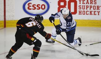 Calgary Flames Juuso Valimaki, left, tries to stop the shot of Winnipeg Jets&#39; Nikolaj Ehlers during the second period of an NHL hockey game Friday, March 26, 2021, in Calgary, Alberta. (Todd Korol/The Canadian Press via AP)