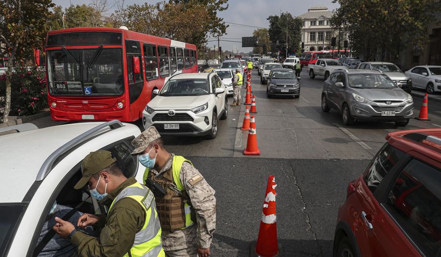 Soldiers check the transit permissions of commuters at a checkpoint in Santiago, Chile, Thursday, March 25, 2021, amid the coronavirus pandemic. Authorities announced the reinstatement of a city-wide lockdown to help contain the spread of COVID-19. (AP Photo/Esteban Felix)