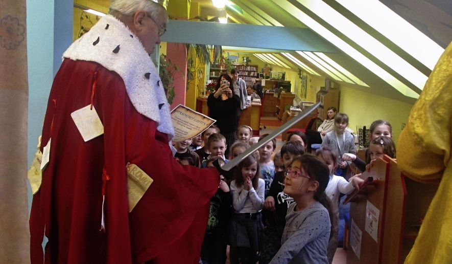 Bookseller Jaromir Vytopil, left, appoints the youngest schoolchildren to the order of readers at a library in Pelhrimov, Czech Republic, Thursday, Feb. 7, 2020. Some 25,000 have been killed by COVID-19 in the hard-hit Czech Republic. Jaromir Vytopil was one of them. His everyday presence in the small Czech town of Pelhrimov was something everybody took for granted for seven decades as he had served the generations of readers. The longest serving Czech bookseller, passed away on Nov 9. 2020, at age of 83. (AP Photo/Miroslav Krsek)