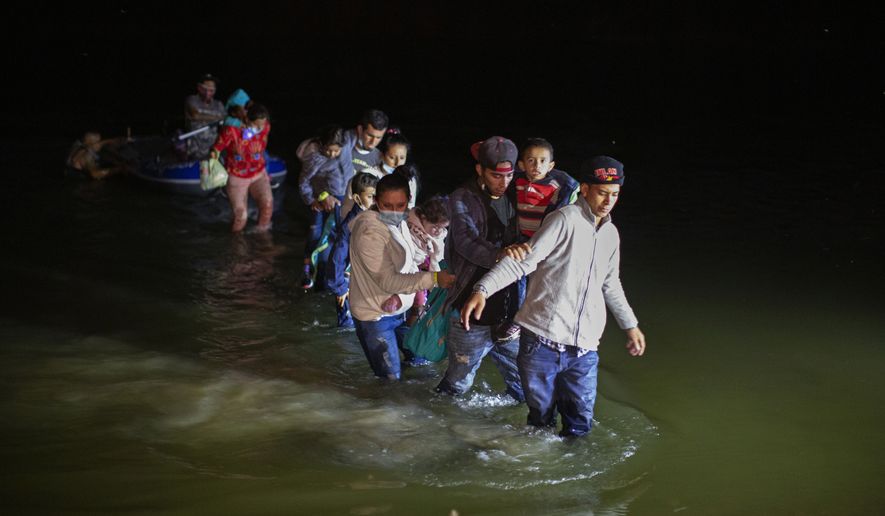 Migrant families, mostly from Central American countries, wade through shallow waters after being delivered by smugglers on small inflatable rafts on U.S. soil in Roma, Texas, Wednesday, March 24, 2021. As soon as the sun sets, at least 100 migrants crossed through the Rio Grande river by smugglers into the United States. (AP Photo/Dario Lopez-Mills)