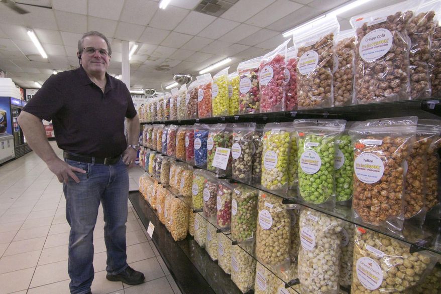 Stephen Canale stands by the wide selection of his gourmet popcorn in Middletown Market, Wednesday, March 17, 2021, in Genoa Township, Mich. The market, which features an entire aisle of It’s So Fluffy popcorn flavors — Canale's up to about 50 different flavors — is among a growing list of local retailers carrying his products. (Gillis Benedict/Livingston County Daily Press & Argus via AP)