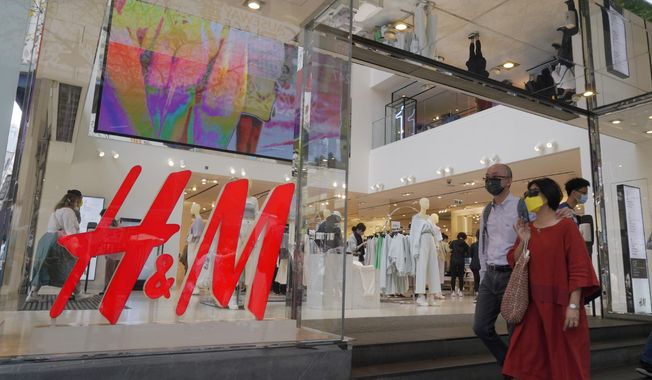 People walk past an H&amp;amp;M clothing store in Hong Kong, Saturday, March 27, 2021. H&amp;amp;M disappeared from the internet in China as the government raised pressure on shoe and clothing brands and announced sanctions Friday, March 26, 2021, against British officials in a spiraling fight over complaints of abuses in the Xinjiang region. (AP Photo/Kin Cheung)