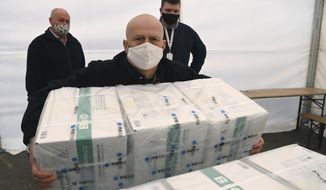 An employee unloads the newly arrived coronavirus vaccines from Chinese pharmaceutical company Sinopharm at the logistics base set up to in the parking lot of the government office in the 13th district of Budapest, Hungary, Monday, March 29, 2021. (Noemi Bruzak/MTI via AP)