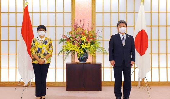 Japan&#39;s Foreign Minister Toshimitsu Motegi, right, and Indonesian Foreign Minister Retno Marsudi, wearing protective face masks, pose for a photograph prior to the Japan Indonesia Foreign Ministers meeting in Tokyo on Monday, March 29, 2021. Indonesian Foreign Minister Retno Marsudi and Defense Minister Prabowo Subianto are in Japan from March 28-30, 2021. (David Mareuil/Pool Photo via AP)