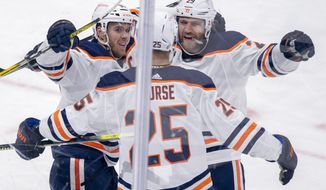 Edmonton Oilers Connor McDavid (97) and Leon Draisaitl (29) congratulate defenceman Darnell Nurse (25) after he score the game winning during overtime NHL hockey action against the Toronto Maple Leafs  in Toronto on Monday March 29, 2021. (Frank Gunn/The Canadian Press via AP)