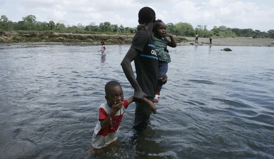 FILE - In this Feb. 10, 2021 file photo, a migrant and his children cross the Tuquesa river after a trip on foot through the jungle to Bajo Chiquito, Darien Province, Panama. According to a UNICEF report published Monday, March 29, 2021, the number of migrant children and teenagers moving north through Panama’s Darien region has risen drastically since 2017. (AP Photo/Arnulfo Franco, File) (AP Photo/Arnulfo Franco, File)