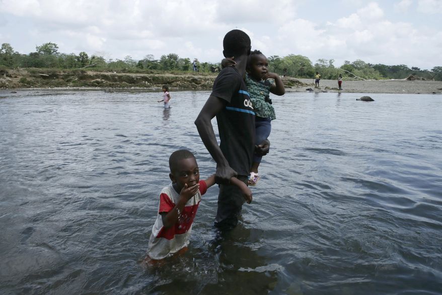 FILE - In this Feb. 10, 2021 file photo, a migrant and his children cross the Tuquesa river after a trip on foot through the jungle to Bajo Chiquito, Darien Province, Panama. According to a UNICEF report published Monday, March 29, 2021, the number of migrant children and teenagers moving north through Panama’s Darien region has risen drastically since 2017. (AP Photo/Arnulfo Franco, File) (AP Photo/Arnulfo Franco, File)