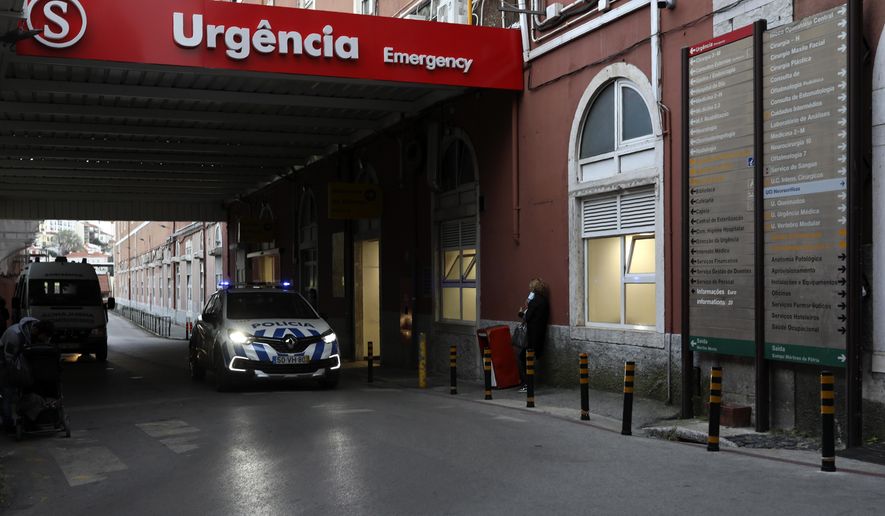 A police car drives past the emergency entrance of the Sao Jose Hospital in Lisbon, Monday, March 29, 2021. An Italian fugitive, convicted in his homeland of ordering the revenge killing of a mobster’s wife, was arrested in Portugal on Monday in a clinic where he was reportedly being treated for COVID-19. (AP Photo/Pedro Rocha)