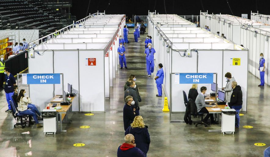 People queue to receive the coronavirus vaccine at the newly opened Covid-19 vaccination centre in the SSE Arena, Belfast, Northern Ireland, Monday March 29, 2021. The vaccination program continues to increase in an effort to control the spread of COVID-19 virus.(Liam McBurney/PA via AP)