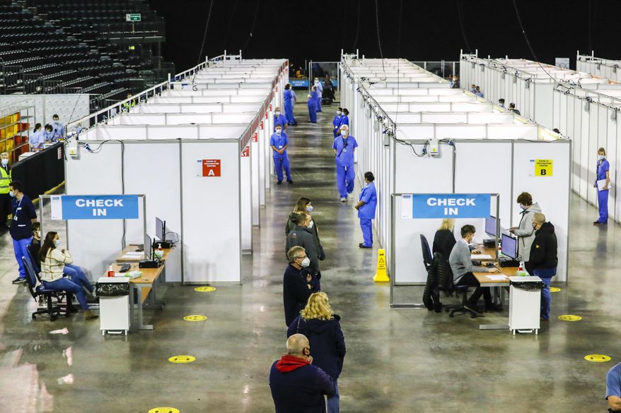 People queue to receive the coronavirus vaccine at the newly opened Covid-19 vaccination centre in the SSE Arena, Belfast, Northern Ireland, Monday March 29, 2021. The vaccination program continues to increase in an effort to control the spread of COVID-19 virus.(Liam McBurney/PA via AP)
