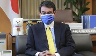 Japanese Vaccine Minister Taro Kono wearing a face mask with Japanese and EU flags on it speaks during an interview in Tokyo, Monday, March 29, 2021. Kono tasked with COVID-19 vaccinations urged the EU to ensure stable shipment of Pfizer vaccines amid distribution uncertainty in a country where the Olympics are coming up in four months. (AP Photo/Koji Sasahara)