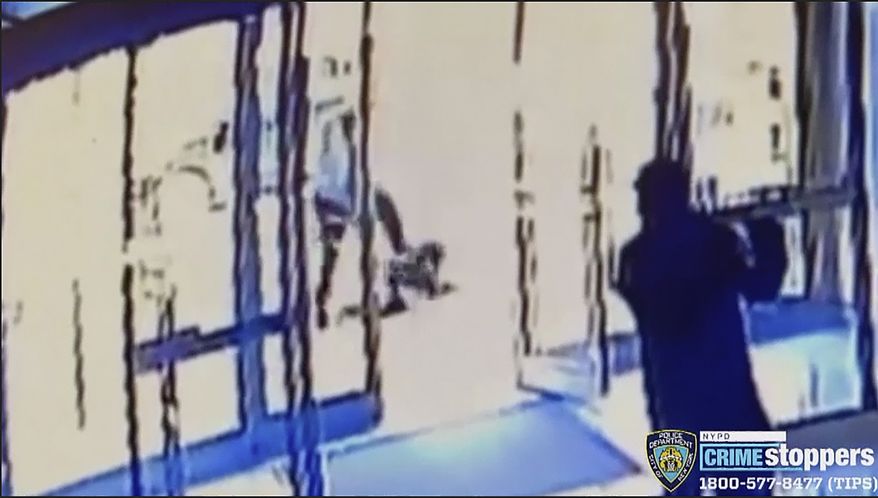 This image taken from surveillance video provided by the New York City Police Department shows a person of interest, background center, assaulting an Asian American woman, on ground, Monday, March 29, 2021, in New York. The 65-year-old woman was walking in midtown Manhattan a few blocks from Times Square on Monday afternoon when a man approached her and kicked her in the stomach, knocking her to the ground, police said. (Courtesy of New York Police Department via AP)