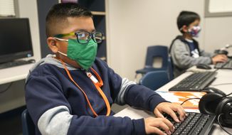 In this Dec. 3, 2020, file photo, students wearing face masks work on computers at Tibbals Elementary School in Murphy, Texas. A new poll from The University of Chicago Harris School of Public Policy and The Associated Press-NORC Center for Public Affairs Research finds that most parents fear that their children are falling behind in school while at home during the pandemic (AP Photo/LM Otero, File)