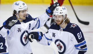 CORRECTS NAME OF PLAYER AT RIGHT TO KYLE CONNOR INSTEAD OF DOMINIC TONINATO - Winnipeg Jets&#39; Mark Scheifele, left, celebrates his goal with teammate Kyle Connor during second-period NHL hockey game action against the Calgary Flames in Calgary, Alberta, Monday, March 29, 2021. (Jeff McIntosh/The Canadian Press via AP)