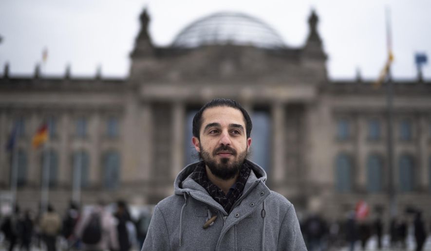 FILE - In this Saturday, Feb. 6, 2021 file photo Tareq Alaows, who is running to become a lawmaker at the German parliament Bundestag poses in front of the Reichstag building in Berlin, Germany. Tareq Alaows who came to Germany as an asylum-seeker in 2015 and launched his campaign to run in Germany's federal election in September for the Green Party said in a statement Tuesday that he had decided to no longer run for parliament for personal reasons. (AP Photo/Markus Schreiber, file)