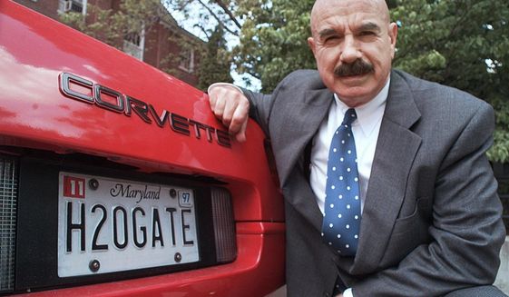 FILE - In this Monday, June 9, 1997, file photo, G. Gordon Liddy kneels next to his Corvette outside the Fairfax, Va., radio station where he broadcasts his syndicated radio talk show. Liddy, a mastermind of the Watergate burglary and a radio talk show host after emerging from prison, has died at age 90. His son, Thomas Liddy, confirmed the death Tuesday, March 30, 2021, but did not reveal the cause. (AP Photo/Ron Edmonds, File)