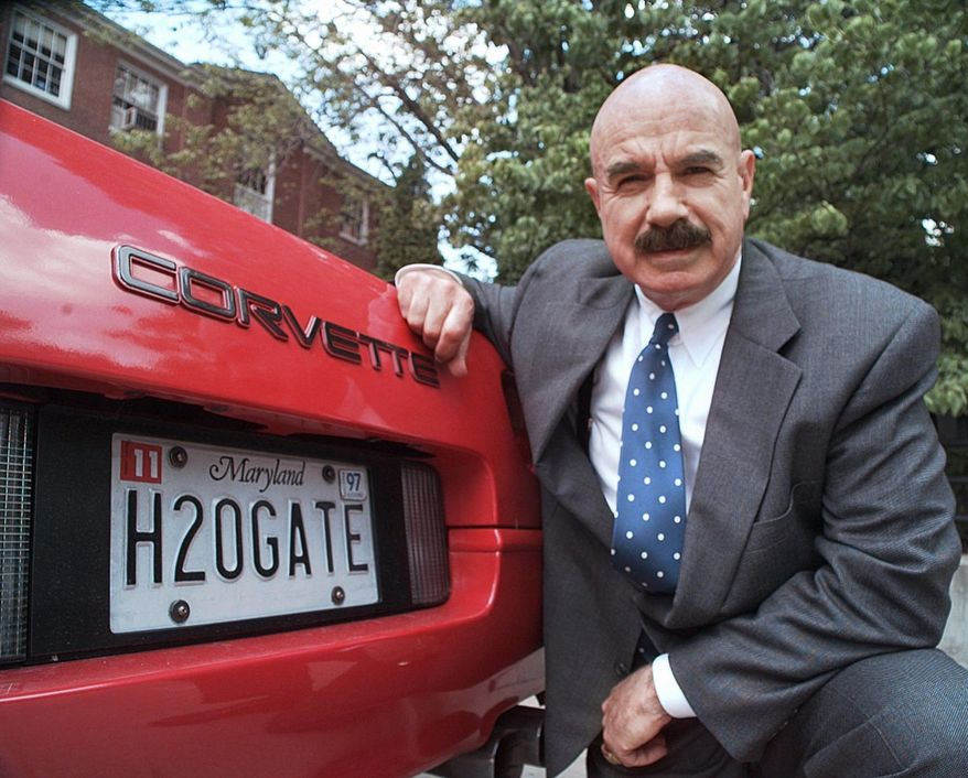 FILE - In this Monday, June 9, 1997, file photo, G. Gordon Liddy kneels next to his Corvette outside the Fairfax, Va., radio station where he broadcasts his syndicated radio talk show. Liddy, a mastermind of the Watergate burglary and a radio talk show host after emerging from prison, has died at age 90. His son, Thomas Liddy, confirmed the death Tuesday, March 30, 2021, but did not reveal the cause. (AP Photo/Ron Edmonds, File)