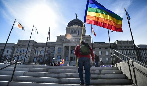 In this March 15, 2021, file photo demonstrators gather on the steps of the Montana State Capitol protesting anti-LGBTQ+ legislation in Helena, Mont. The Montana Senate advanced Tuesday, March 30, 2021, a bill that would ban transgender athletes from participating in school and college sports according to the gender with which they identify, but amended it to be voided if the federal government withholds federal funding from the state due to the measure. (Thom Bridge/Independent Record via AP) **FILE**