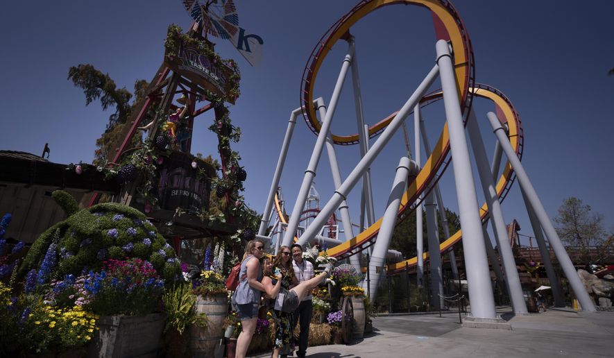 Visitors pose for photos during the Knott's Taste of Boysenberry Festival at Knott's Berry Farm in Buena Park, Calif., Tuesday, March 30, 2021. Massive Los Angeles County can reopen even more businesses, California public health officials announced Tuesday. The county of 10 million people was one of several counties, including neighboring Orange County, that moved into the state's second-least restrictive orange tier amid low coronavirus case rates. (AP Photo/Jae C. Hong)