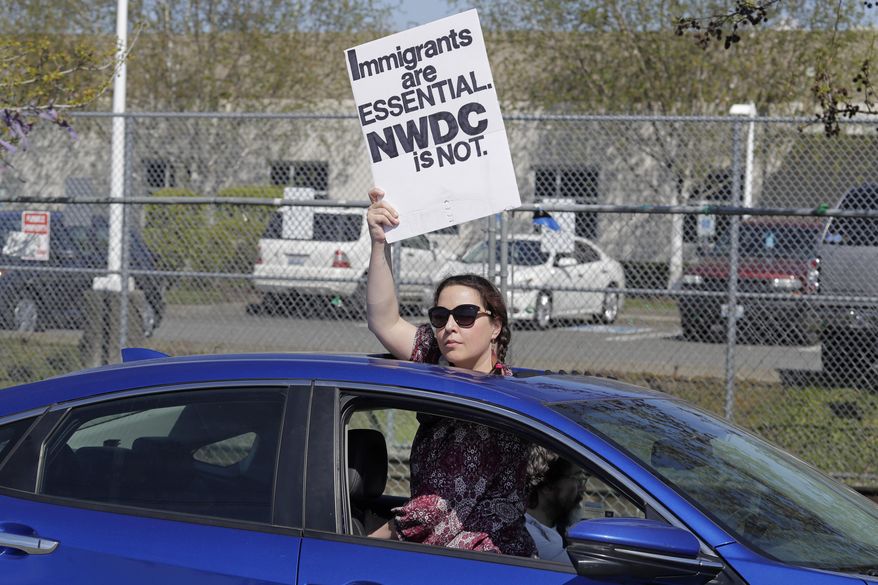 FILE - In this April 15, 2020 file photo a protester holds a sign she looks out from the sunroof of a car during a protest at the Northwest Detention Center a facility privately operated on behalf of the U.S. Immigration and Customs Enforcement agency, in Tacoma, Wash. The Washington Legislature has approved a bill aimed at shutting down one of the country's largest for-profit, privately run immigration jails. (AP Photo/Ted S. Warren,File)